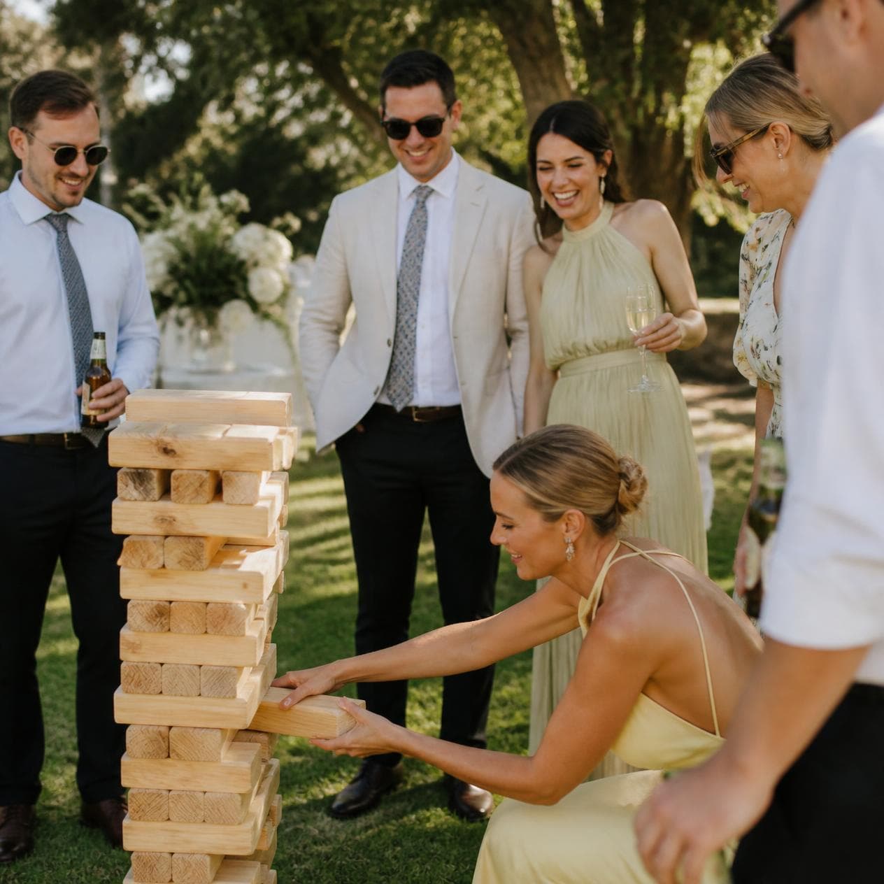 Guests playing giant Jenga on the lawn at a wedding